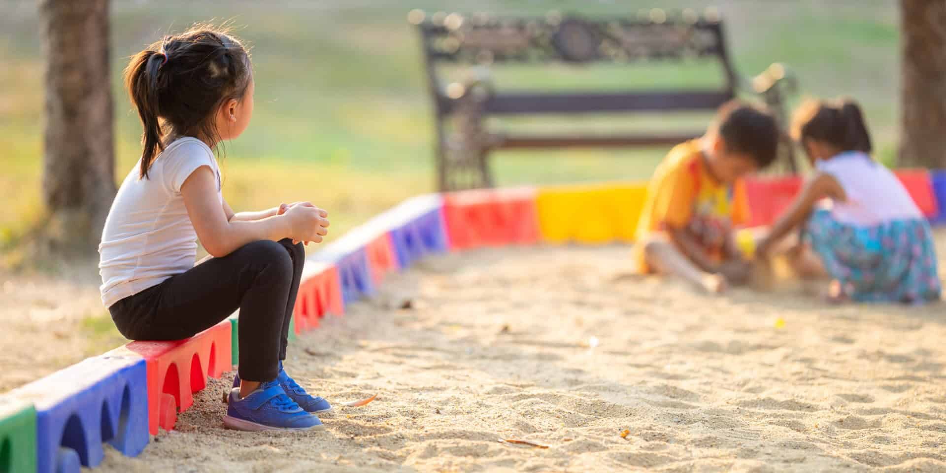 Little,Girl,Sitting,Lonely,Watching,Friends,Play,At,The,Playground.the